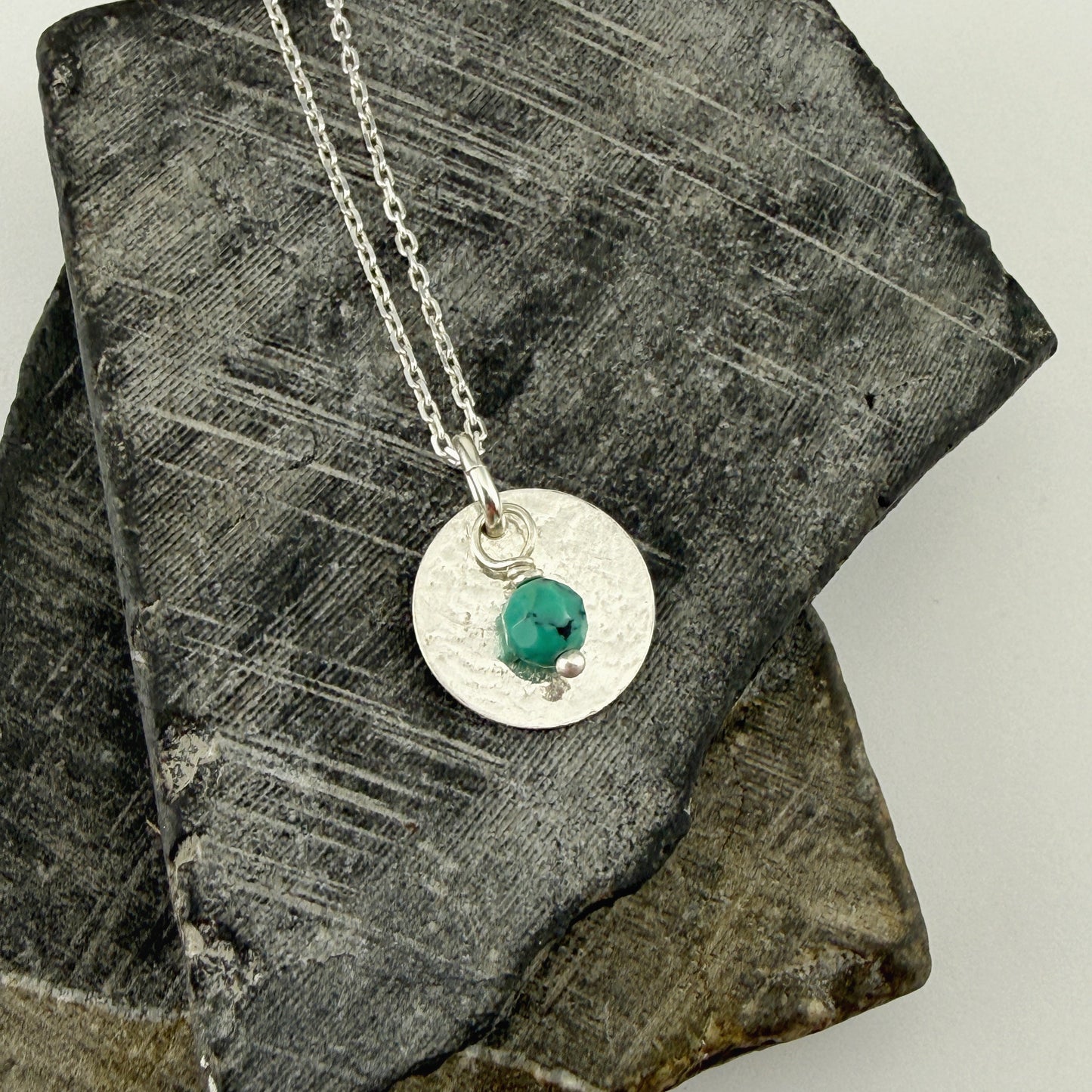 Sterling silver necklace December Birthstone Turquoise Circle Pendant Necklace on a textured stone surface