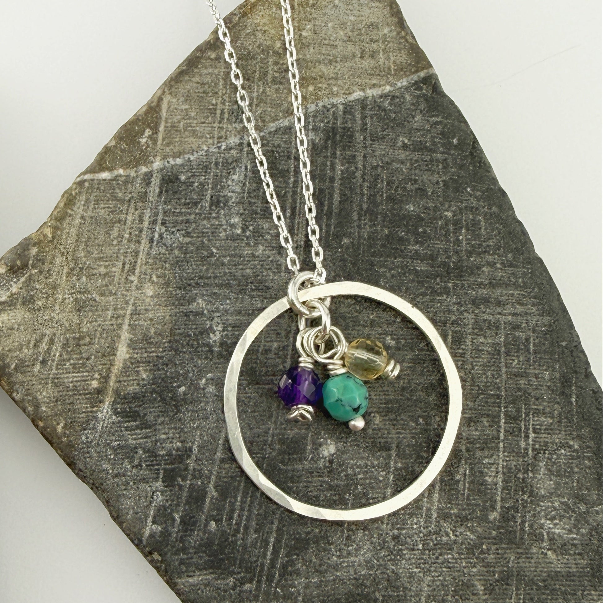 Silver charm necklace with for mother's day on a textured stone surface